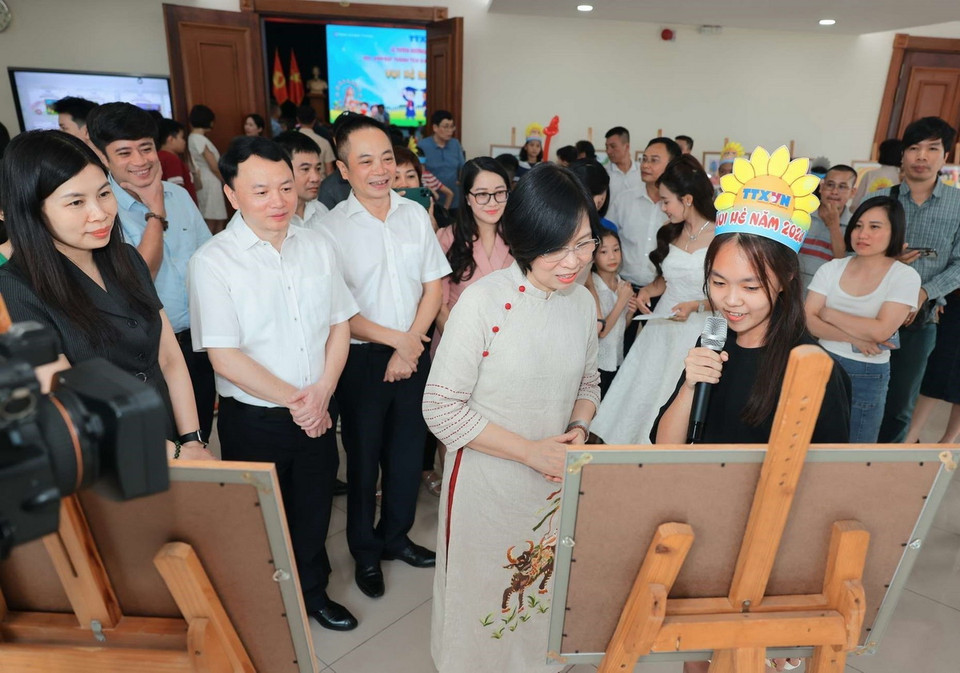 Tổng Giám đốc TTXVN Vũ Việt Trang và đại biểu nghe giới thiệu các tác phẩm tranh trưng bày của con cán bộ, công nhân viên TTXVN. (Ảnh: Hoàng Hiếu/TTXVN)