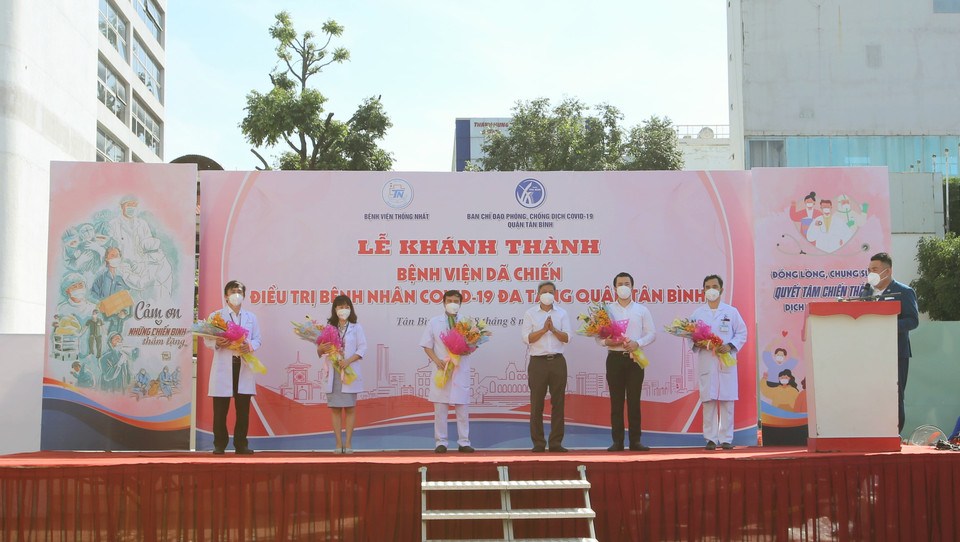 Thứ trưởng Bộ Y tế Nguyễn Trường Sơn tặng hoa động viên các bác sỹ tại Bệnh viện dã chiến điều trị bệnh nhân COVID-19 đa tầng quận Tân Bình. (Ảnh: Thành Chung/TTXVN)