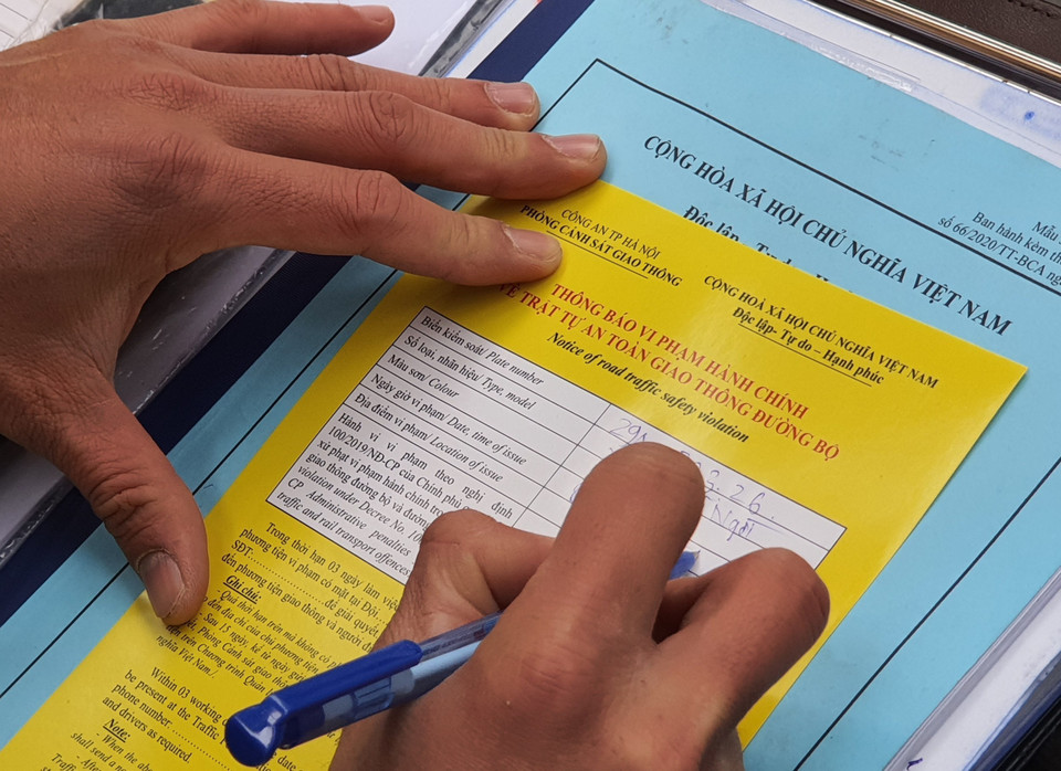 Cảnh sát giao thông viết biên bản phạt nguội đối với phương tiện dừng, đỗ trái phép trên phố Bà Triệu. (Ảnh: Doãn Tấn/TTXVN)