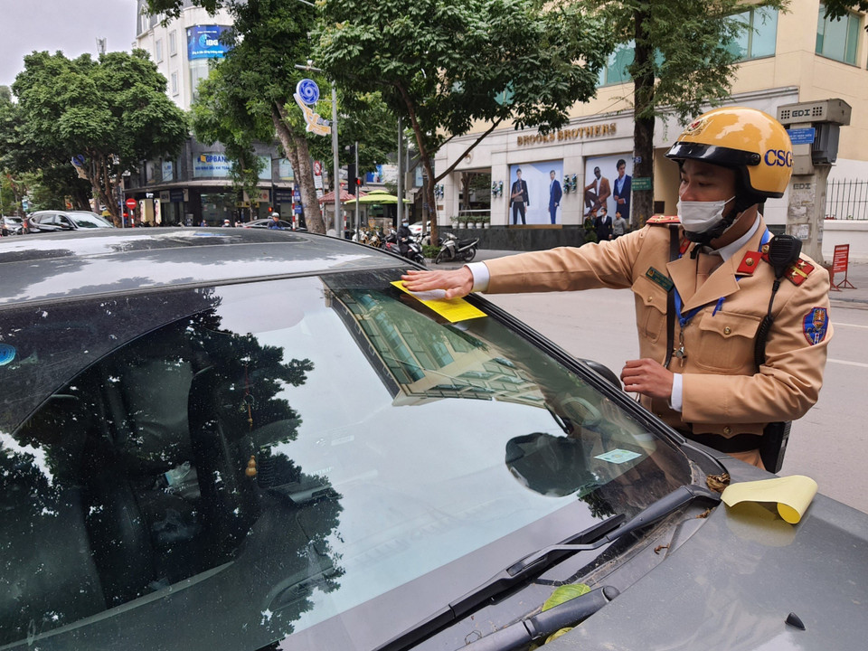 Cảnh sát giao thông dán phạt nguội đối với phương tiện dừng, đỗ trái phép trên phố Bà Triệu. (Ảnh: Doãn Tấn/TTXVN)