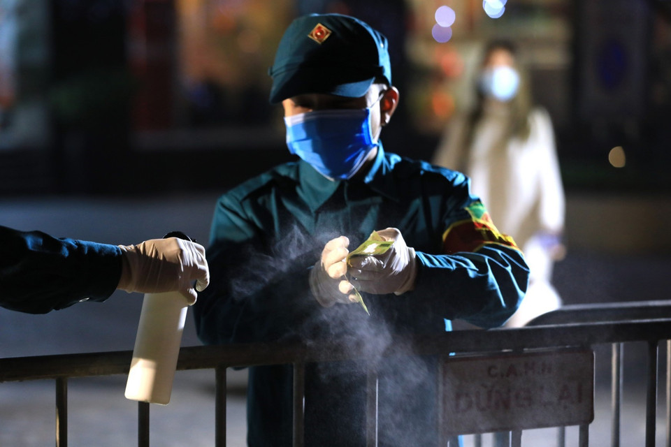 Lực lượng chức năng phun khử khuẩn tất cả đồ dùng hay bất cứ thứ gì chuyển vào trong tòa chung cư Sky City Tower. (Ảnh: Thành Đạt/TTXVN)