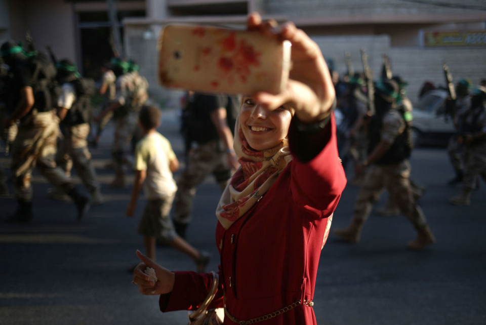 Thiếu nữ Palestine chụp ảnh selfie tại một cuộc diễu hành của trung đoàn Ezzedine al-Qassam, một cánh vũ trang của Hamas ở Gaza. (Ảnh: AFP)