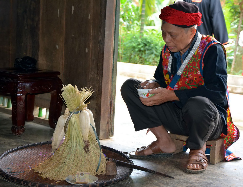 Thầy cúng làm lễ rồi dùng nước phun vào cụm lúa để cầu cho mưa thuận, gió hòa. (Ảnh: Thế Duyệt/TTXVN)