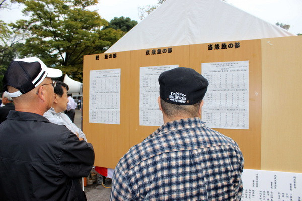 Khách tham quan xem bảng thẩm định những chú cá Ranchu được giới thiệu tại hội chọ. (Ảnh: Hữu Thắng/Vietnam+)