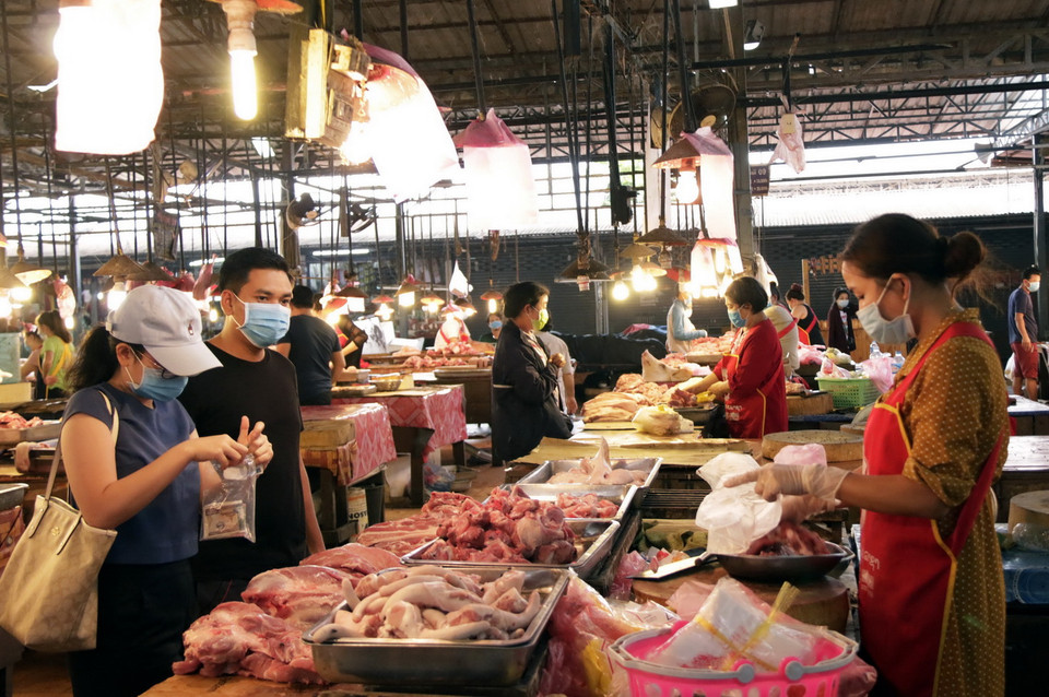 Cả người bán và người mua hàng đều tuân thủ quy định đeo khẩu trang khi ra đường. (Ảnh: Phạm Kiên/Vietnam+)