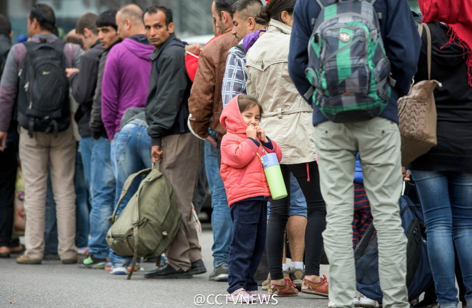 Nhiều em bé được bố mẹ dẫn đi trong dòng người nhập cư. 
