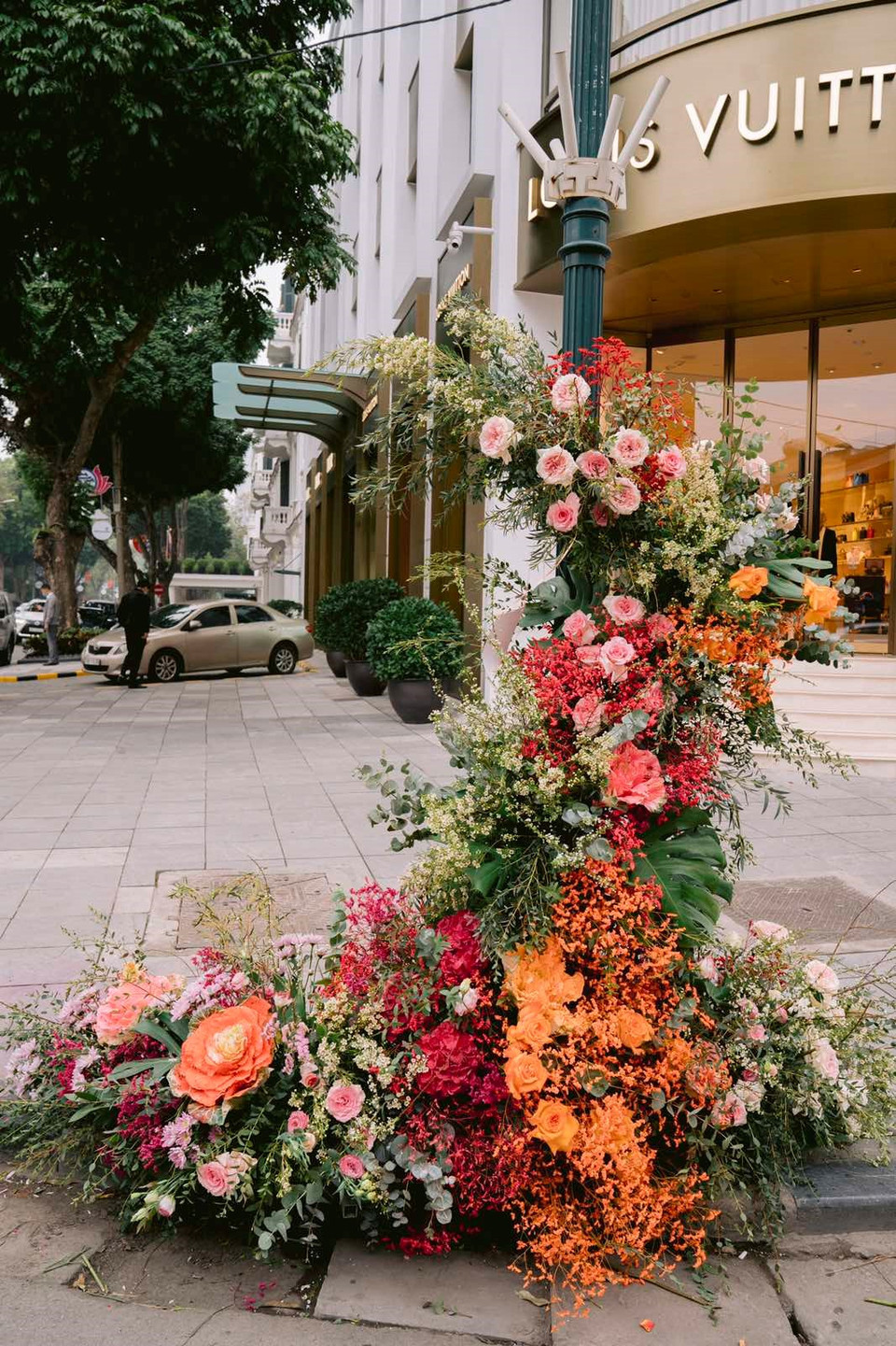 Một cột đèn trước khách sạn Metropole "khoác" áo mới dệt bằng những thảm hoa tươi. Tập đoàn Ecopark, đơn vị thực hiện hoạt động trang trí này cho biết, ý tưởng biến cột điện thành cột hoa xuất phát từ mong muốn đưa thiên nhiên vào phố thị. "Khi có thiên nhiên chạm vào, những thứ mờ nhạt, đơn điệu như cây cột điện, biển chỉ đường cũng trở nên xinh đẹp, có giá trị," vị đại diện tập đoàn Ecopark chia sẻ. (Ảnh: Ngọc Thành)