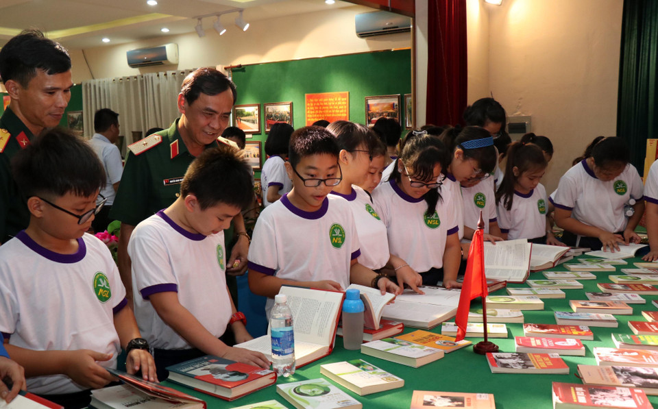 Thiếu tướng Nguyễn Minh Hoàng, Phó Chính ủy Quân khu 7 và các em học sinh tại gian trưng bày sách về Chủ tịch Hồ Chí Minh. (Ảnh: Xuân Khu/TTXVN)