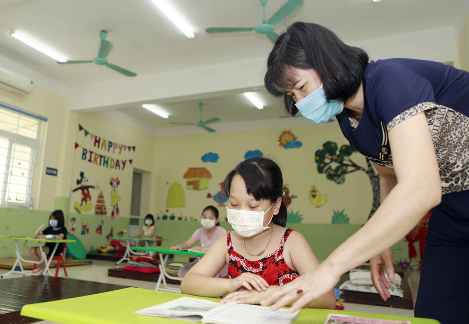 Một phụ huynh hướng dẫn các con tại phòng trong một buổi học. (Ảnh: Hoàng Hùng/TTXVN)