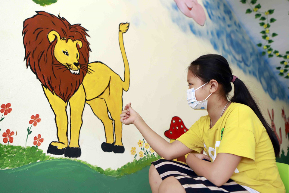 Một bé gái "nói chuyện" với vua sư tử trong lúc đợi xét nghiệm SARS-CoV-2. (Ảnh: Hoàng Hùng/TTXVN)