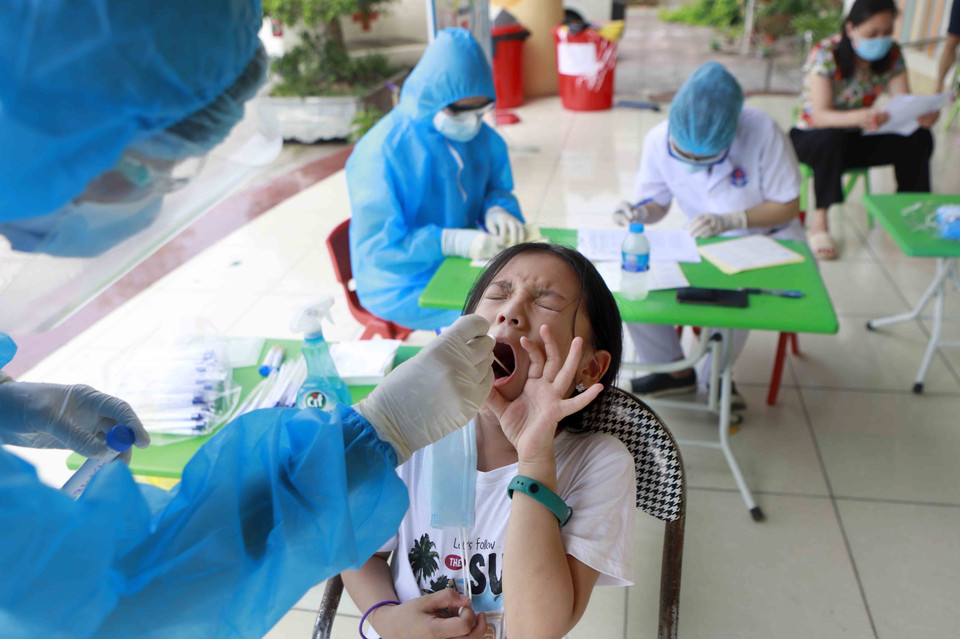 Nhân viên y tế xét nghiệm virus SARS-CoV-2 lần 3 cho học sinh Trường tiểu học Lưu Quý An. (Ảnh: Hoàng Hùng/TTXVN)