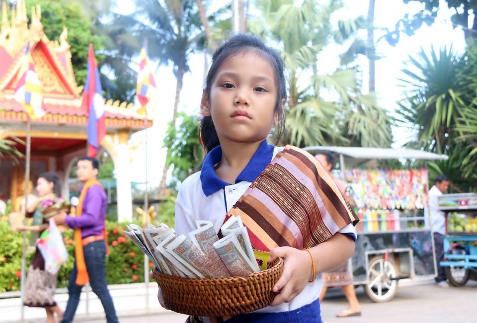 Một em gái được mẹ đưa đi hành lễ Tắt bạt. (Ảnh: Phạm Kiên/Vietnam+)