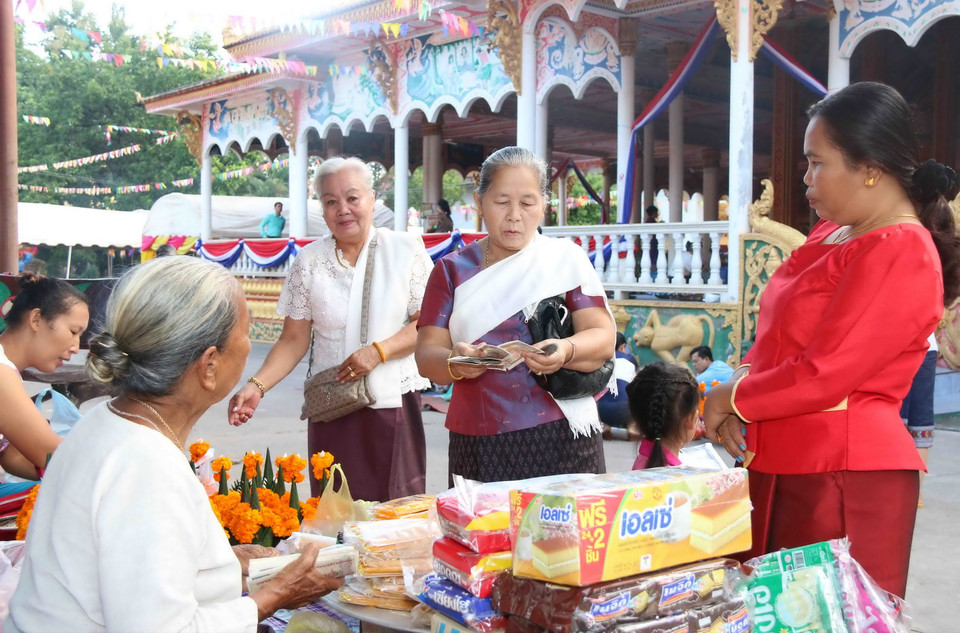Rất đông người dân Lào từ sáng sớm đã đến chùa để chuẩn bị cho lễ Tắt bạt (dâng lễ cho nhà sư). (Ảnh: Phạm Kiên/Vietnam+)