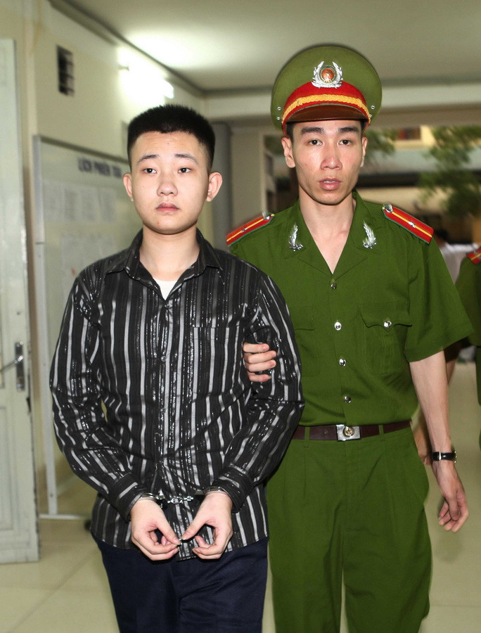 Dẫn giải bị cáo Đào Quang Khánh, nhân viên bảo vệ Thẩm mỹ viện Cát Tường vào phòng xử án. (Ảnh: Doãn Tấn/TTXVN)