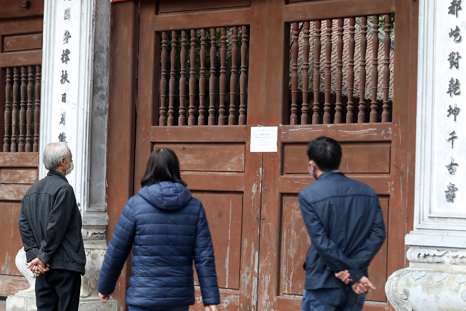 Người dân đọc thông báo đóng cửa tại Đền - Đình Kim Liên. (Ảnh: Phan Tuấn Anh/TTXVN)