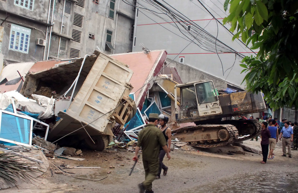 Một chiếc xe tải và một chiếc máy xúc ở gần đó cũng bị tòa nhà sập đổ đè lên. (Ảnh: Quốc Đạt/TTXVN)