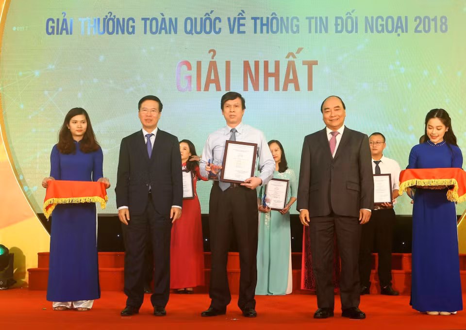 Thủ tướng Nguyễn Xuân Phúc và Ủy viên Bộ Chính trị, Bí thư Trung ương Đảng, Trưởng ban Tuyên giáo Trung ương, Trưởng ban Chỉ đạo Công tác thông tin đối ngoại Trung ương Võ Văn Thưởng trao giải nhất Giải thưởng toàn quốc thông tin đối ngoại năm 2018 cho tác giả Lê Trí Dũng (TTXVN), ngày 7/6/2019, tại Hà Nội. (Ảnh: Doãn Tấn - TTXVN)