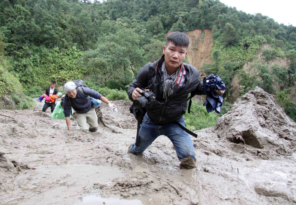 Phóng viên Quý Trung cùng đồng nghiệp trên đường đi đưa tin lũ lụt ở Lai Châu hồi tháng 8/2018. (Ảnh: TTXVN)