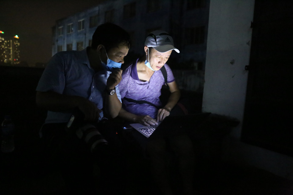 Các phóng viên ảnh Huy Hùng, Doãn Tấn tác nghiệp và gửi ảnh ngay tại hiện trường vụ cháy ở Công ty CP bóng đèn phích nước Rạng Đông. (Ảnh: TTXVN)