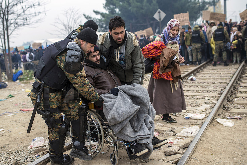 Cảnh sát giúp đỡ người đàn ông nhập cư đi xe lăn vượt qua biên giới.