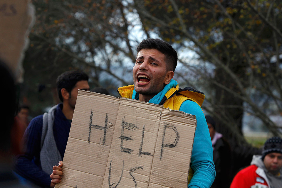 Người đàn ông cầm tấm bảng kêu gọi sự giúp đỡ tại biên giới Hy Lạp-Macedonia. (Ảnh: Reuters)