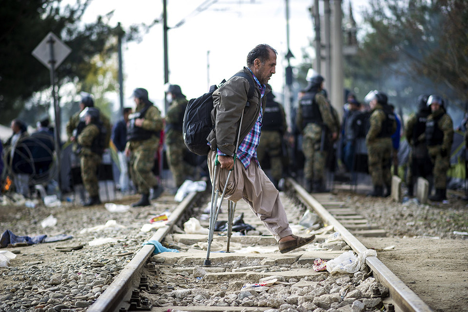 Người đàn ông khuyết tật đi qua đám đông cảnh sát chống bạo động Macedonia. (Ảnh: AFP)