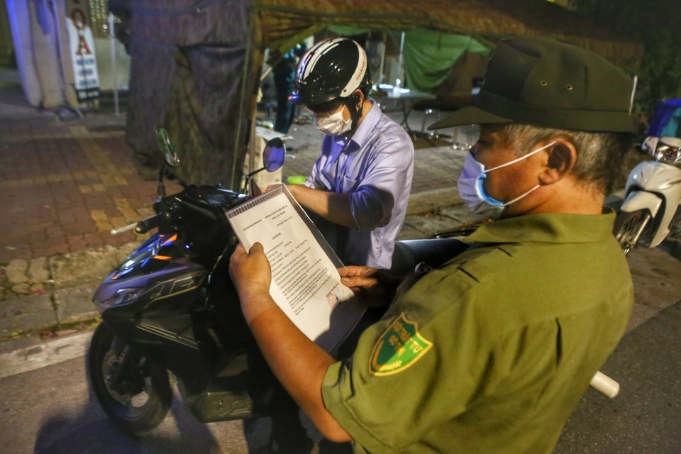 Lực lượng chức năng kiểm tra giấy tờ người đi đường tại chốt kiểm soát phố Huế. (Ảnh: Tuấn Đức/TTXVN)