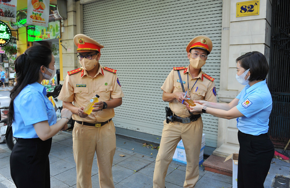 Trao tặng đồ uống cho lực lượng công an Thủ đô đang thực hiện nhiệm vụ tại 6 tổ tuần tra kiểm soát lưu động trên các tuyến đường. (Ảnh: Minh Đức/TTXVN)