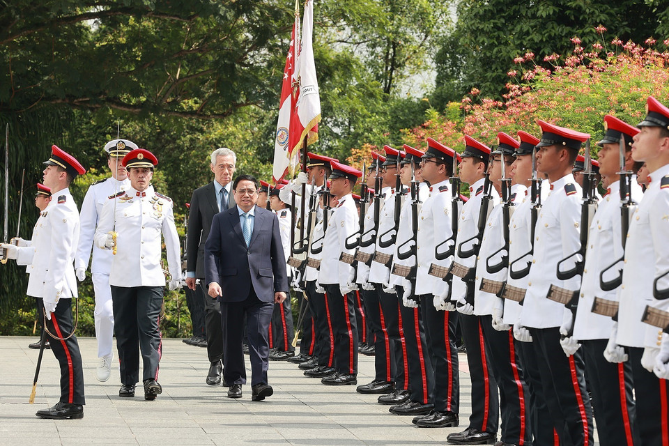 Thủ tướng Phạm Minh Chính và Thủ tướng Singapore Lý Hiển Long duyệt đội danh dự. (Ảnh: Dương Giang/TTXVN)