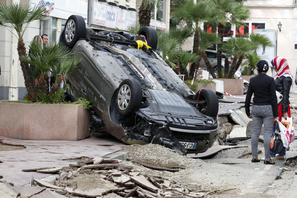 Hai phụ nữ đứng nhìn chiếc xe bị lật úp trên phố sau trận lụt ở Cannes, miền Nam nước Pháp. (Ảnh: AP)