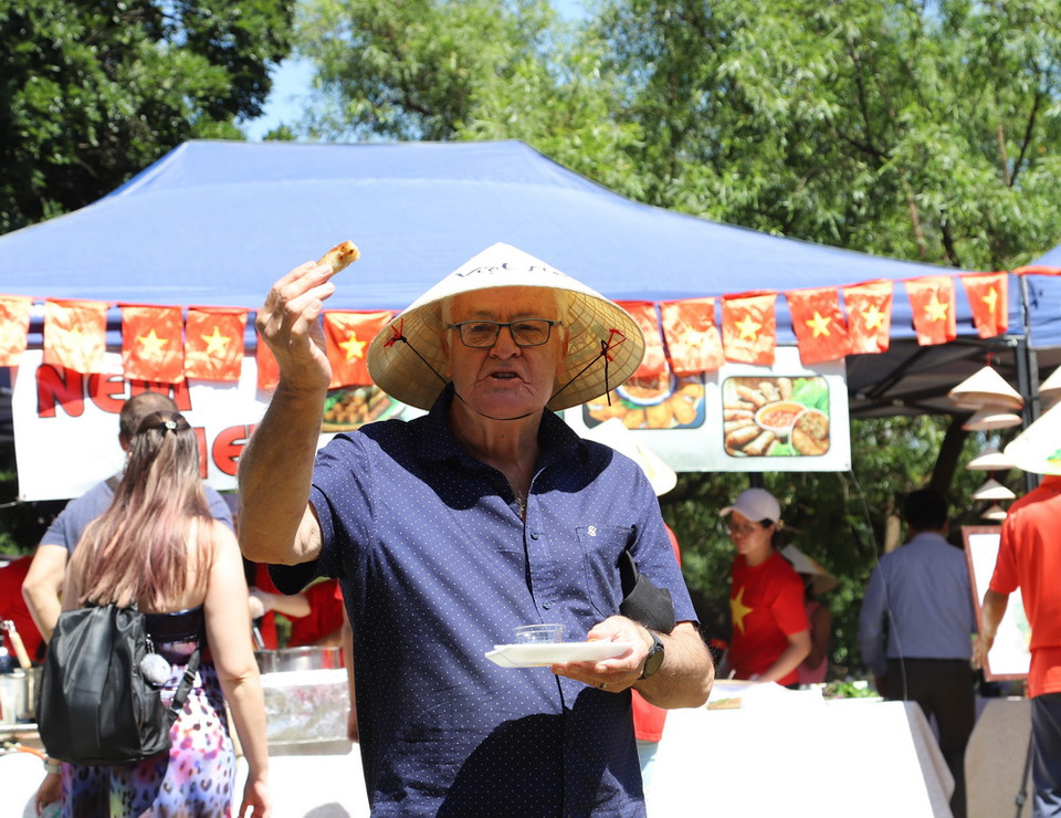 Ông Stoffel van Zyl, người Nam Phi vui mừng vì được thưởng thức món ăn Việt Nam, được đội chiếc nón lá Việt Nam mà trước đây ông chỉ có thể được biết qua sách báo, tranh ảnh và YouTube. (Ảnh: Hồng Minh/TTXVN)