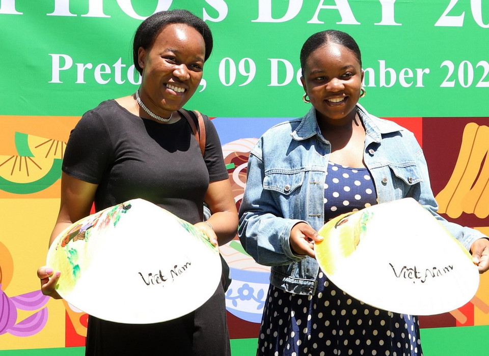 Hai người bạn Nam Phi thích thú chụp ảnh lưu niệm cùng nón lá Việt Nam. (Ảnh: Hồng Minh/TTXVN)