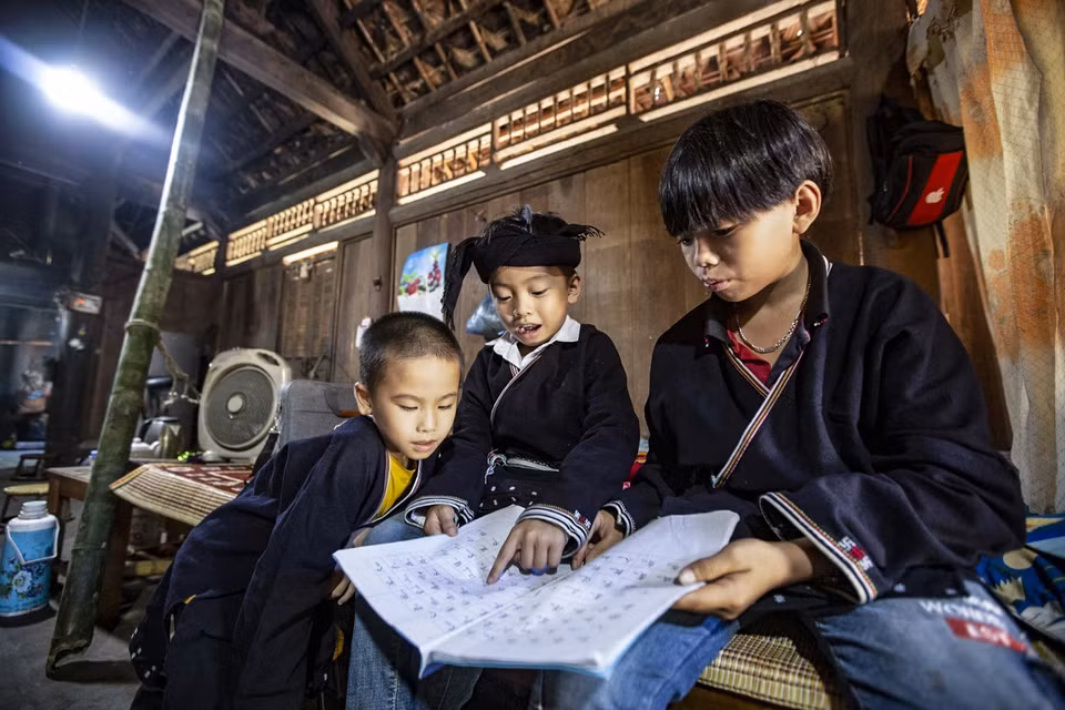 Ba người cháu được ông Lý Văn Hềnh truyền dạy chữ Dao mỗi ngày tại nhà. (Ảnh: Trọng Đạt/TTXVN)