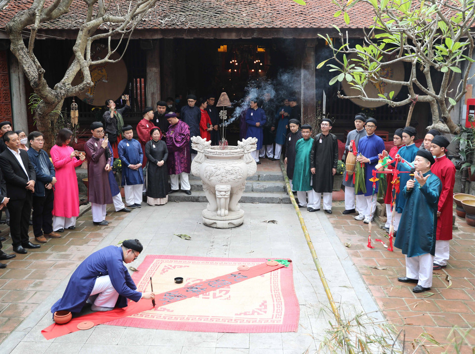 Viết thư pháp để treo trên cây nêu ngày Tết. Ảnh: Thanh Tùng - TTXVN