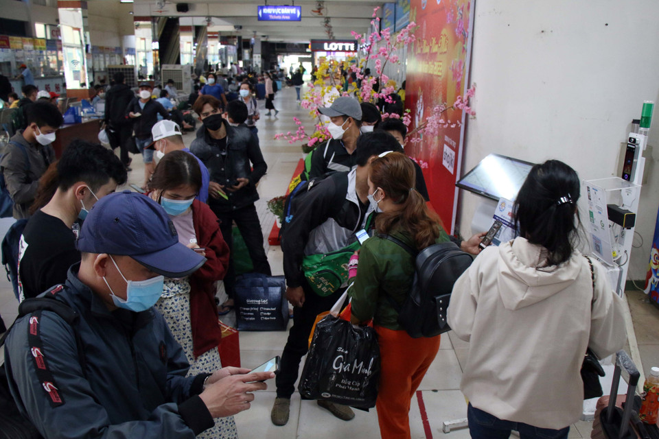 Hành khách thực hiện khai báo y tế trên điện thoại trước khi ra khu vực nhà xe. (Ảnh: Tiến Lực/TTXVN)