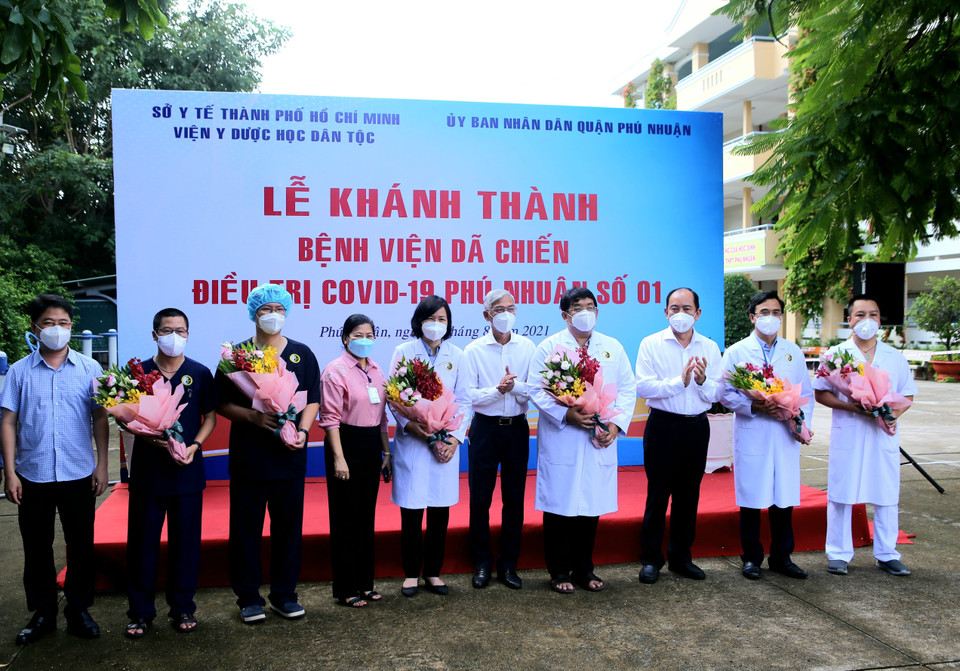 Lãnh đạo Ủy ban Nhân dân Thành phố Hồ Chí Minh và Sở Y tế tặng hoa, động viên các y, bác sỹ làm nhiệm vụ tại Bệnh viện dã chiến điều trị bệnh nhân COVID-19 số 01 Phú Nhuận. (Ảnh: Thành Chung/TTXVN)