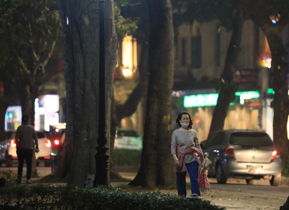 Một người dân không đeo khẩu trang đúng cách tại phố Lê Thái Tổ tối 16/1. (Ảnh: Hoàng Hiếu/TTXVN)