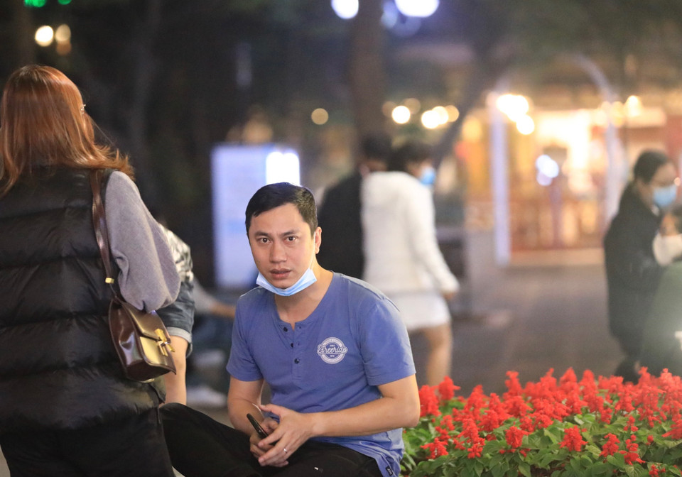 Một người dân vẫn đeo khẩu trang không đúng cách khi vui chơi tại khu vực Hồ Gươm. (Ảnh: Hoàng Hiếu/TTXVN)