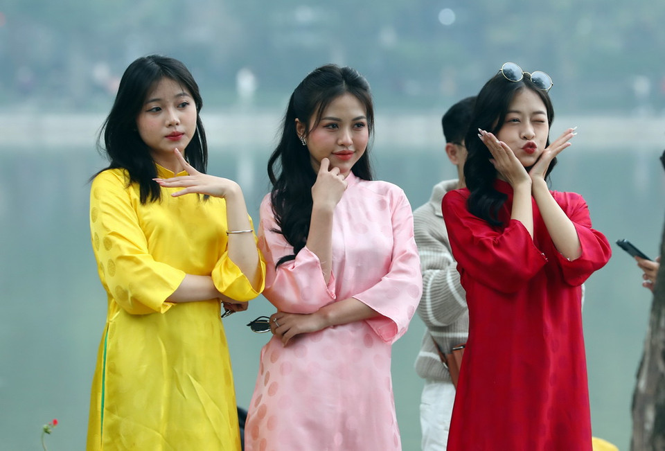 Các thiếu nữ tạo dáng bên hồ Hoàn Kiếm trong ngày cuối cùng của năm 2023. (Ảnh: Phạm Kiên/TTXVN)