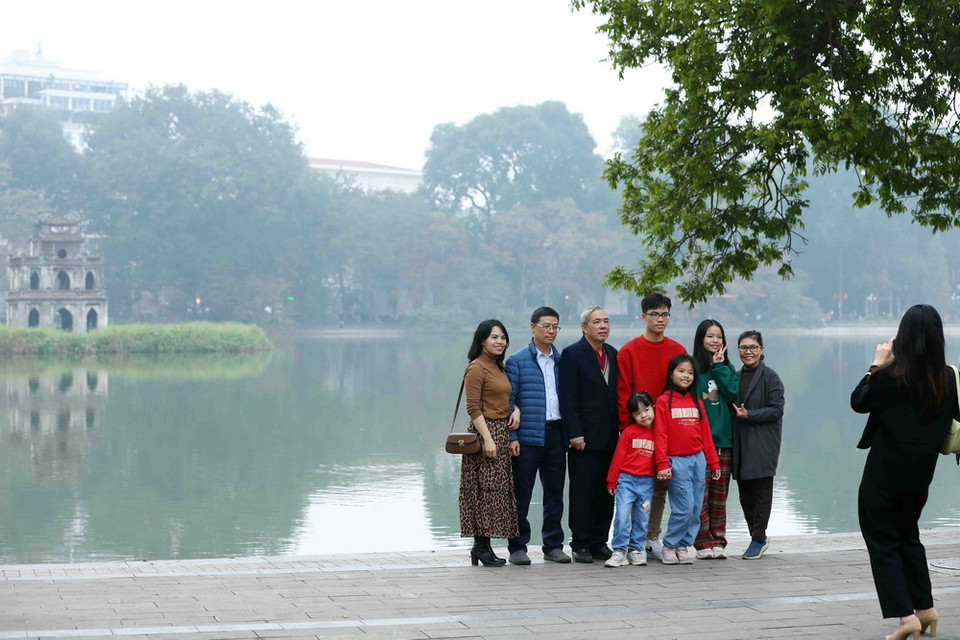Người dân Hà Nội có truyền thống chụp ảnh lưu niệm bên Hồ Hoàn Kiếm trong những ngày cuối cùng của năm 2023. (Ảnh: Phạm Kiên/TTXVN)