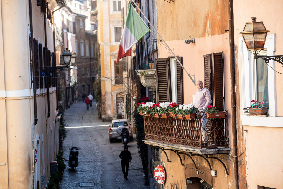 Một người đàn ông đứng ngắm đường phố từ ban công căn hộ ở Rome, Italy. (Ảnh: EPA)