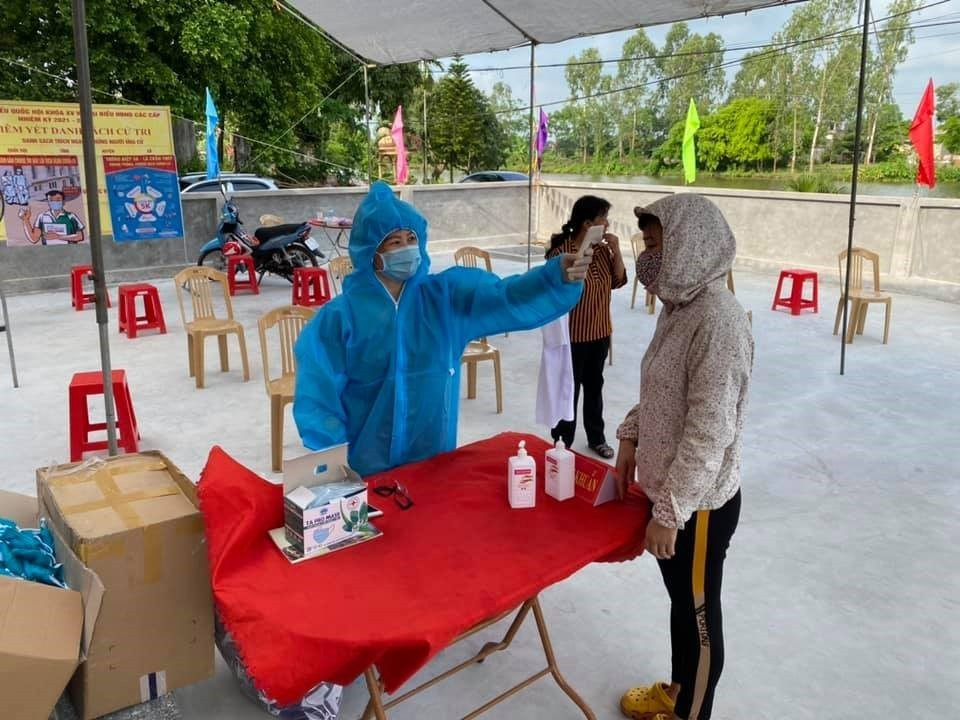 Kiểm tra thân nhiệt của cử tri tước khi vào điểm bỏ phiếu. (Ảnh: Đại Nghĩa/TTXVN)