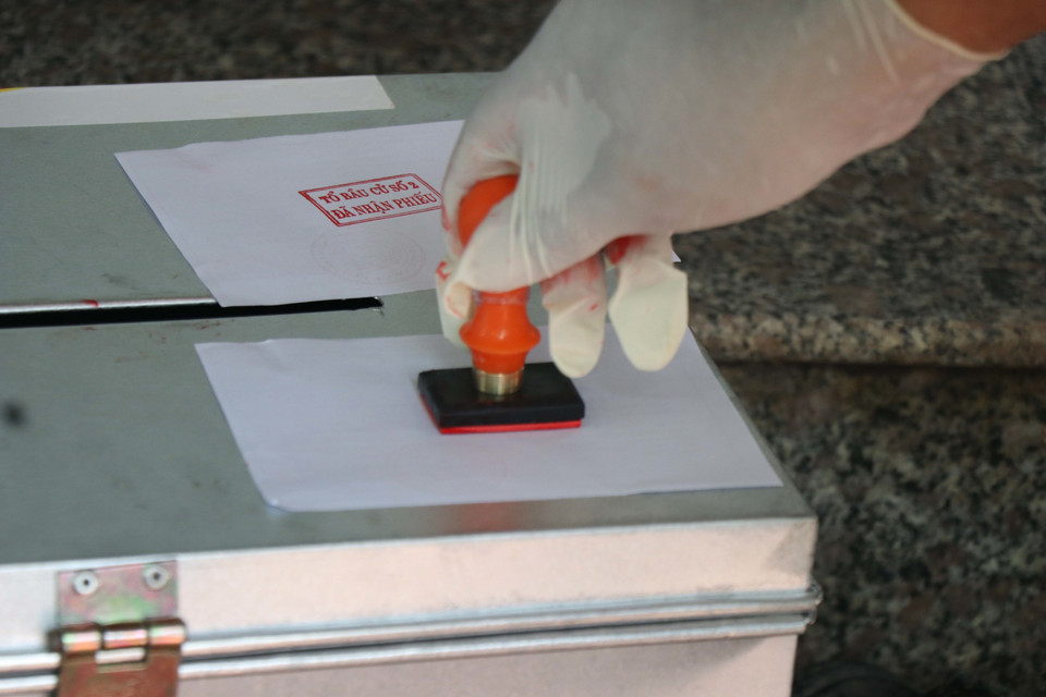 Tổ đại biểu đóng dấu xác nhận hoàn thành bầu cử của các trường hợp cử tri đang cách ly tại nhà. (Ảnh: Thanh Thương/ TTXVN)