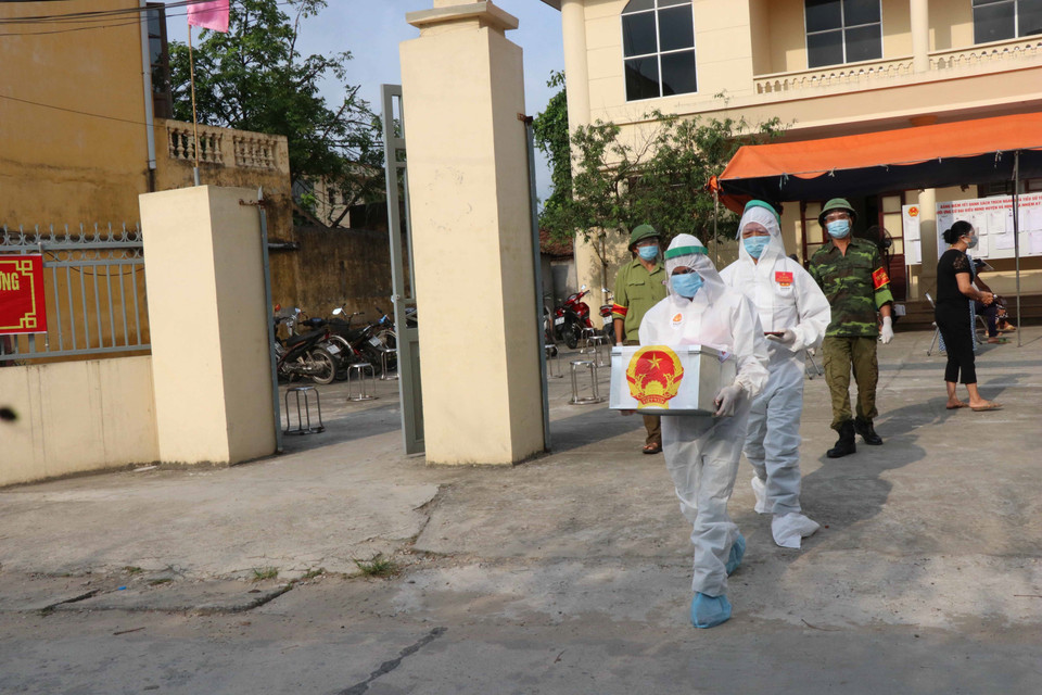 Tổ bầu cử mang hòm phiếu phụ cho cử tri cách ly tại nhà bầu cử. (Ảnh: Thanh Thương/TTXVN)