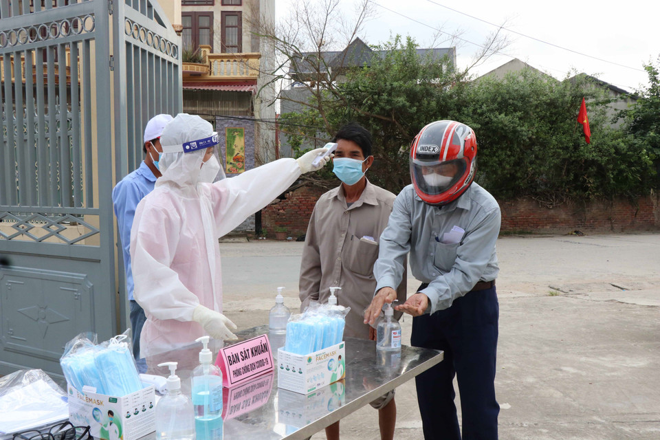 Kiểm tra thân nhiệt cho cử tri đến bầu cử tại Mão Điền. (Ảnh: Thanh Thương/TTXVN)