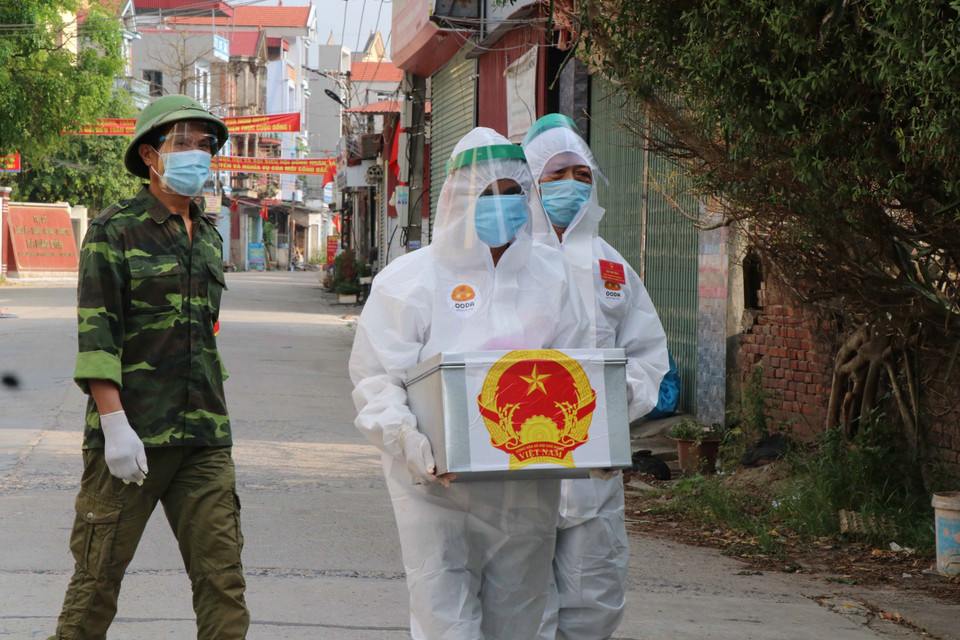 Tổ bầu cử mang hòm phiếu phụ cho cử tri cách ly tại nhà bầu cử. (Ảnh: Thanh Thương/TTXVN)