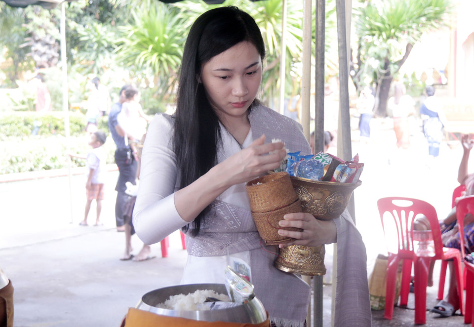 Thiếu nữ Lào đang thực hiện nghi thức Tak Bath để dâng lễ cho các nhà sư và những người đã khuất. (Ảnh: Phạm Kiên/Vietnam+)