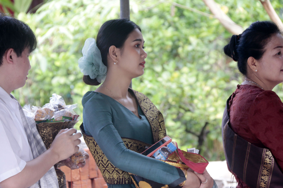 Thiếu nữ Lào đang xếp hàng để chờ tới lượt vào thực hiện nghi thức Tak Bath để dâng lễ cho các nhà sư và những người đã khuất. (Ảnh: Phạm Kiên/Vietnam+)