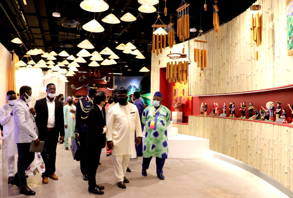 Tổng thống Sierra Leone tỏ ra thích thú trước bức tường tre trưng bày các búp bê thủ công mặc trang phục dân tộc truyền thống của Việt Nam.