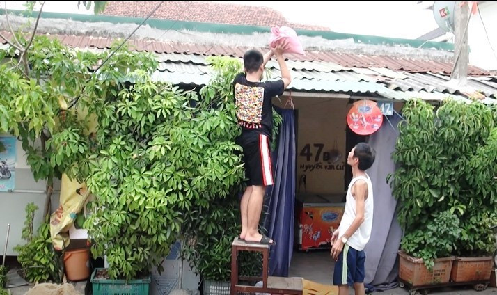 Người dân che chắn bao tải cát lên mái nhà ứng phó với gió bão.(Ảnh: Võ Dung/TTXVN)